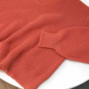 Close-up view of a casual terracotta V-neck ribbed knit pullover sweater texture.