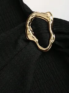 Detailed macro view of textured black knit fabric with an organic gold metal buckle.