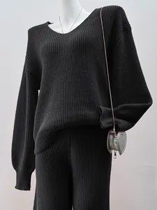 Detailed view of a black V-neck knitted sweater and matching pants set on a white mannequin.