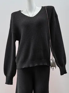 Detailed view of the black V-neck knitted sweater and matching pants set on a white mannequin