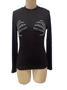 Detailweergave zwarte geribbelde top met lange mouwen en zilveren schedelhand strass.