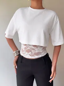 Detail of a white cropped short-sleeve T-shirt with intricate lace patchwork hemline.