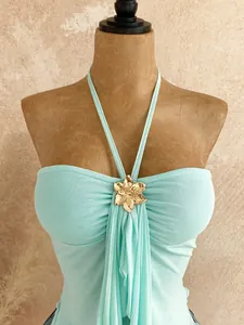 Close-up of mint green mesh halter tube top featuring an elegant golden flower buckle