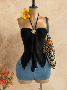 Front view of black mesh halter top with ruffled swallowtail hem and floral brooch