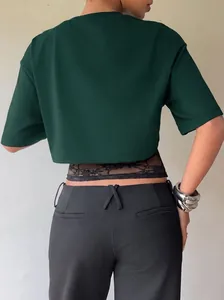 Back view of a dark green crop top with black lace patchwork and slim fit design.