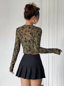 Elegante top de malla transparente verde oliva con manga larga y detalles de flores negras.