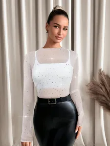 Detailed view of women's white rhinestone mesh top paired with stylish black leather pants
