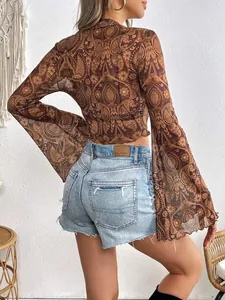 Dettaglio del top in mesh marrone con stampa paisley e maniche a campana ampie