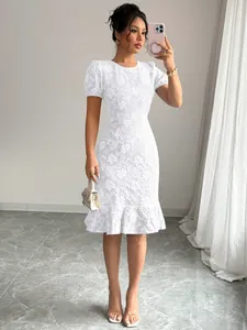Close-up of white floral textured dress with puff sleeves and ruffled hem details.