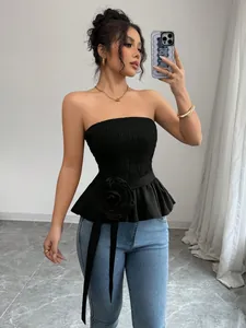 Detailed view of black smocked tube top with a large decorative flower at the waist