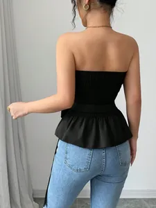 Back view of a chic black peplum tube top styled with light blue jeans in a bright room