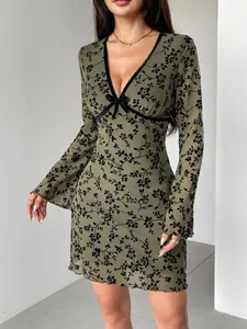 Detailed view of green mesh dress with black floral flocking and elegant V-neck design.
