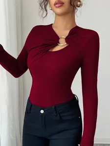 Detail of burgundy slim-fit top with asymmetric cutout and gold metal ring detail.