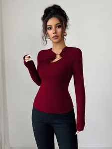 Close-up detail of burgundy slim fit top featuring asymmetrical cutout and gold ring