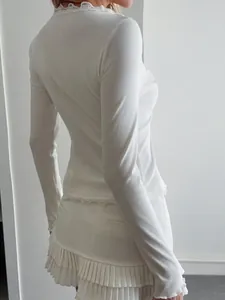 Close-up detail of the ribbed fabric and lace trim on a white long sleeve top