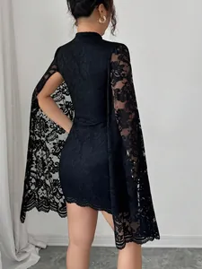 Back view of black lace mini dress featuring unique slit cape sleeves and mock neck