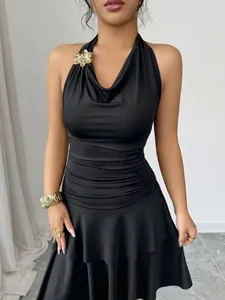 Primer plano de vestido halter negro con cintura plisada y hebilla dorada de flor