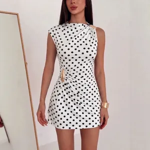 Detailansicht eines ärmellosen Polka-Dot-Kleides mit eleganten goldenen Metallschnallen.
