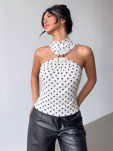 Stylish model posing in a white sleeveless halter neck top with black polka dots and gold buckle