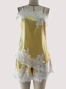 Detailed close-up of yellow satin camisole set featuring elegant white lace floral applique.