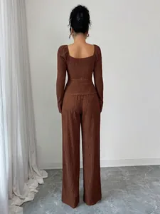 Dettaglio posteriore di top e pantaloni in maglia marrone operata in ambiente minimalista