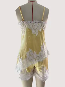 Back view of yellow satin pajama set with intricate white lace details on camisole and shorts.