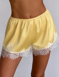 Detailed view of yellow satin pajama shorts featuring exquisite white eyelash lace trim