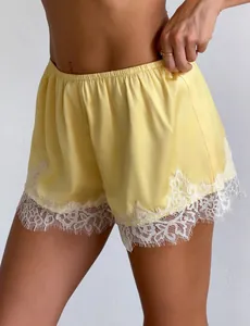 Detailed view of yellow satin pajama shorts featuring elegant white eyelash lace trim.