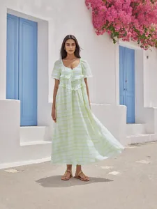 Elegante abito lungo a quadretti verde chiaro con volant in un ambiente mediterraneo