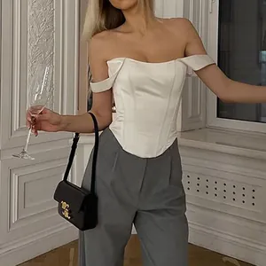 Detailed look at a white satin fishbone corset top paired with elegant grey trousers.