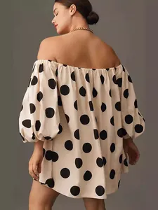 Fashionable beige off-the-shoulder mini dress featuring large black polka dots and puff sleeves