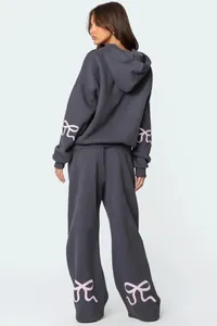 Back view of grey oversized tracksuit with pink bow patterns on sleeves and legs