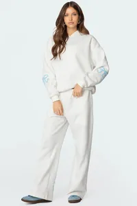Model wearing a white oversized hooded tracksuit set with blue bow sleeve details