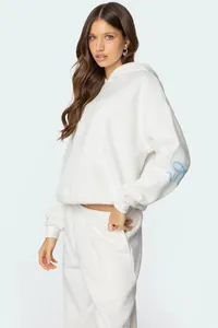 Oversized white hooded sweatshirt featuring a blue bow detail on the sleeve