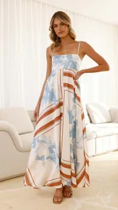 Elegant model posing in a white floral print maxi dress with blue and brown patterns.
