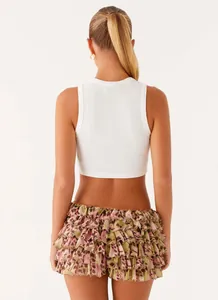 Detailed back view of a tiered ruffle mini skirt with leopard print and a white crop top