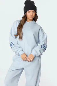 Woman wearing oversized light blue hoodie and sweatpants set with navy bow sleeve detail