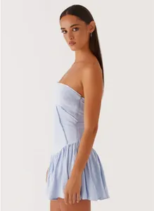 Side view profile of a light blue strapless backless pleated mini dress on a model.
