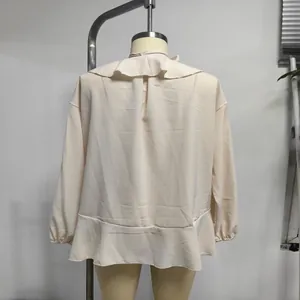 Elegante vista posteriore di camicetta in chiffon a balze beige con maniche a campana su manichino