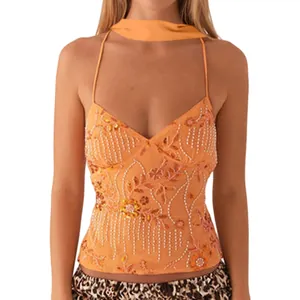 Nahaufnahme eines orangefarbenen Halter-Tops mit floraler Stickerei und glänzenden Pailletten.