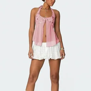 Λεπτομέρεια ενός ροζ σιφόν halter top με πούλιες και ένα κομψό μπροστινό σκίσιμο.