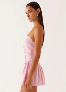 Side profile detail of a stylish pink strapless mini dress with a pleated hemline