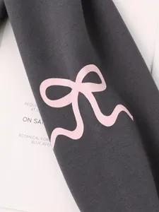 Close-up detail of a grey long sleeve sweatshirt featuring a large pink bow print design