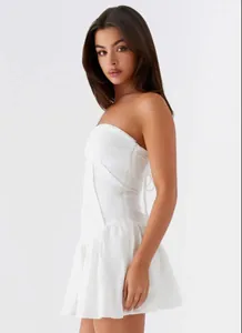 Detailed side view of a white strapless backless pleated mini dress on a model