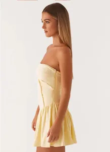 Side view of a yellow strapless mini dress featuring a slim waist and ruffled hem details.