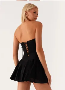 Close-up back detail of a black tube top pleated mini dress with lace-up design