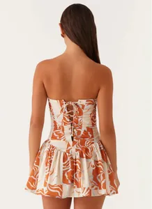 Close-up detail of the back lace-up corset design on a strapless floral print mini dress