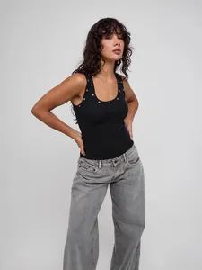 Black U-neck ribbed tank top with silver eyelets worn by a model in a studio set