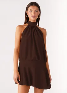 Detail view of brown sleeveless halter neck dress with pleated neckline and gold hoops.