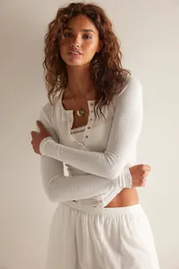 Detail van een wit wafelgebreid vest met lange mouwen en knoopjes voor dames mode